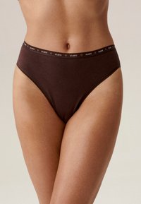 Brązowe, wysokie majtki bikini wykonane z miękkiego materiału, z kontrastującym elastycznym paskiem z logo. Gładka faktura, minimalistyczny design.