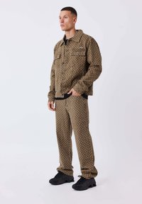 Set di giacca e pantaloni in denim marrone a motivo con vestibilità rilassata, caratterizzato da un design testurizzato e cinque tasche. Abbinato a sneakers nere.