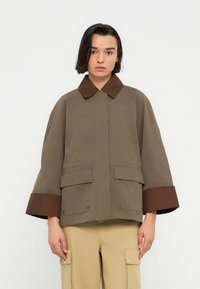 Καφέ και μπεζ μπουφάν με στρογγυλεμένο γιακά, μεγάλες μπροστινές τσέπες και φαρδιά μανίκια. Κατασκευασμένο από υφή υφάσματος με λείο φινίρισμα.