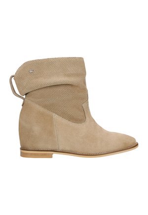 Bottine beige en daim, avec un empiècement perforé et un talon compensé. Semelle plate contrastante avec des détails de couture.