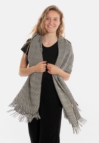 Écharpe à motif chevron gris et noir avec des bords frangés, en tissu texturé, portée sur les épaules.