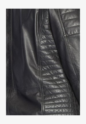Zwart leren jack met gladde en gestructureerde panelen, voorzien van gestikte accenten op de schouders en zijkanten. Op maat gemaakte ontwerp met gestikte naden.