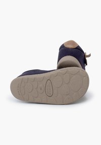 Scarpa in camoscio blu navy con un accento in pelle beige sul tallone. Presenta una suola in gomma flessibile con una superficie testurizzata per una presa sicura.