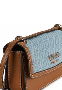 Borsa a mano in pelle marrone con patta in tessuto blu decorato, caratterizzata da un logo dorato e dettagli di cuciture, e una forma rettangolare elegante.
