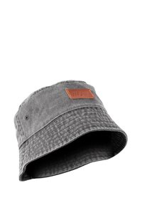 Gray bucket hat made of textured fabric, featuring a wide brim and a rectangular brown leather patch with embossed design on the front.