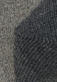 Tejido de punto que presenta una mezcla de tonos grises y beiges, con un patrón diagonal texturizado y un acabado suave.