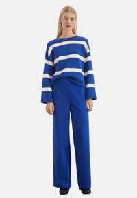 Blau-weißer gestreifter Pullover mit langen Ärmeln, kombiniert mit einfarbigen blauen weiten Hosen. Weiche Textur, lässige Passform, minimale Hardware.