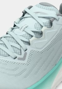 Bottines de sport bleu clair avec une tige en tissu texturé, des lacets assortis et une semelle turquoise, avec l'étiquette "FWD VIA" sur la languette.