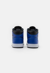 Par de zapatillas altas en azul, negro y blanco, mostradas desde la parte posterior sobre un fondo blanco liso.