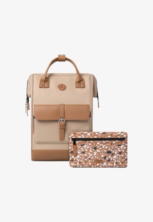 Sac à dos en tissu beige avec des accents en cuir marron, doté d'un rabat à l'avant et d'une pochette zippée amovible avec un motif multicolore.