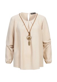 Crèmekleurige blouse van textuurstof, met lange mouwen en een sleutelgat-sluiting aan de achterkant. Vergezeld van een bruine ketting met metalen accenten.