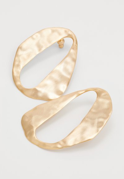 Pair of irregularly shaped, hammered gold-tone metal hoop earrings with a matte finish on a plain white background.