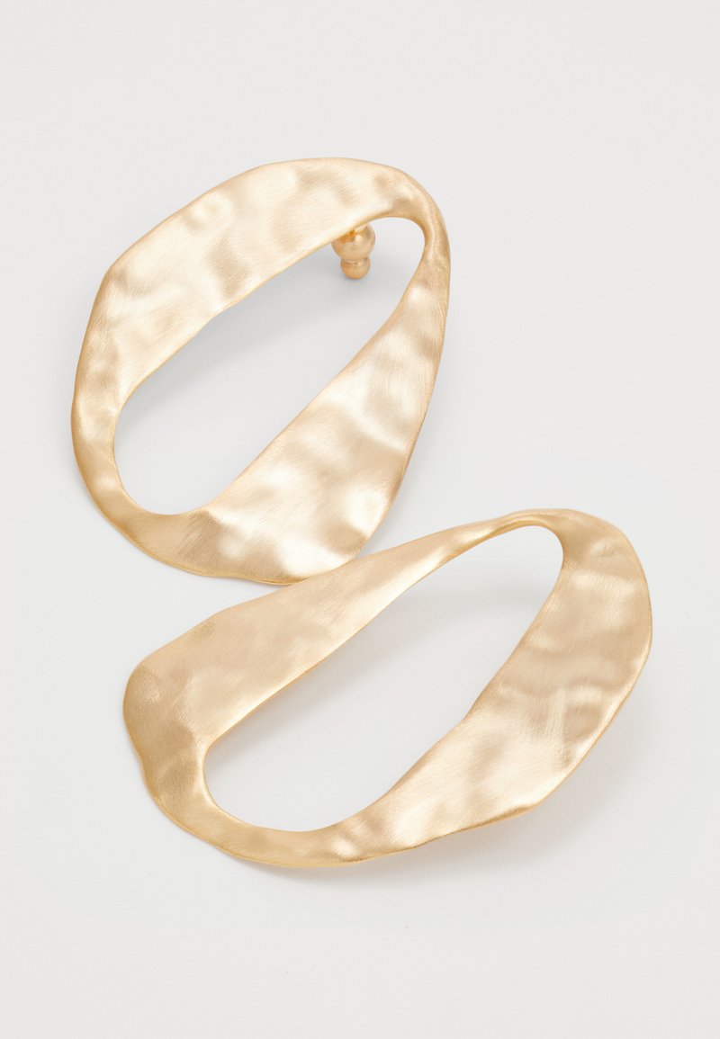 Pair of irregularly shaped, hammered gold-tone metal hoop earrings with a matte finish on a plain white background.