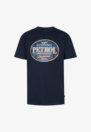 Marineblå t-shirt med et hvidt og orange "PETROL"-motiv; båret med lyseblå jeans og hvide sneakers. Glat bomuldsstof, afslappet pasform.