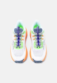 Ζευγάρι λευκά αθλητικά παπούτσια με πορτοκαλί σόλες, πράσινες λεπτομέρειες, γκρι κορδόνια και μπλε ετικέτες έλξης με την ένδειξη «Saucony Xodus Ultra».