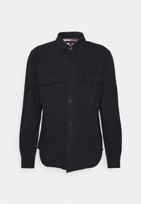 Camicia nera da uomo a maniche lunghe con bottoni, due tasche sul petto e colletto classico, esposta su uno sfondo bianco semplice.