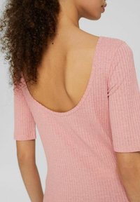 Abito rosa a coste con maniche corte e scollatura bassa sul retro, che mette in risalto un tessuto testurizzato e una silhouette aderente.