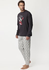 Blusa de manga larga en color carbón con un gráfico de cartoon; pantalones grises con pequeños estampados de cartoons en rojo y negro; material cómodo, corte relajado.
