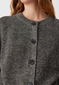 Cardigan lavorato a maglia in nero e grigio con un motivo testurizzato, caratterizzato da un collo rotondo e bottoni neri lungo la parte anteriore.