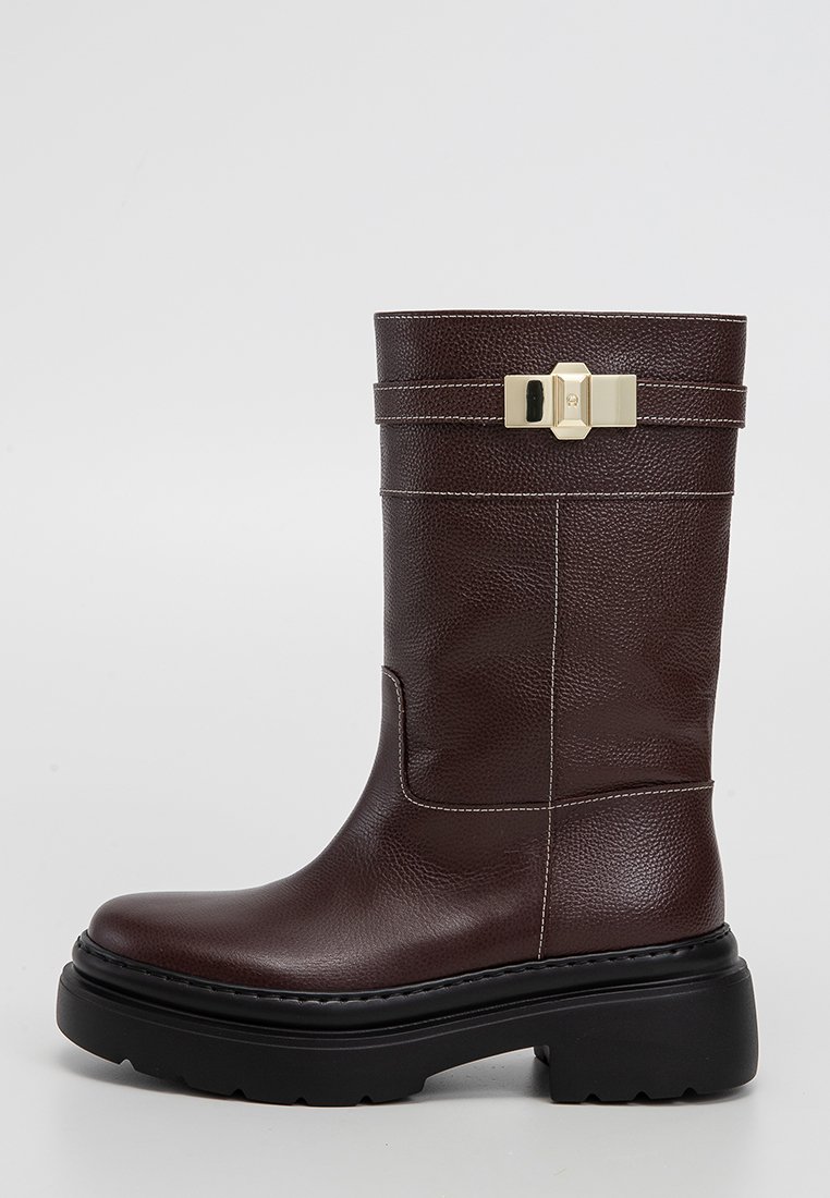 Braune Lederstiefel bis zum Knie mit strukturiertem Finish, schwarzer Plateausohle und goldener Schnallenakzent. Weiße Nähte entlang des Körpers.