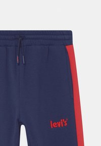 Navy Sweatpants mit roten Seitenpanelen, elastischem Bund und Kordelzug. Mit gesticktem roten "Levi's"-Logo auf dem linken Oberschenkel.
