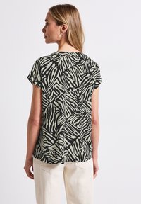 Camicia a maniche corte in stampa zebra nera e beige, realizzata in tessuto leggero con una vestibilità comoda e orlo arrotondato.