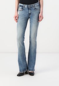 Blugi evazați de culoare albastru deschis, din denim. Au o talie medie, ușor decolorată și detalii de cusătură pe buzunare. Asortați cu pantofi cu toc negri.