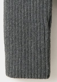 Gros plan d’un tissu en laine grise tricotée avec une texture côtelée verticale et une petite ouverture de poche sur le côté droit.