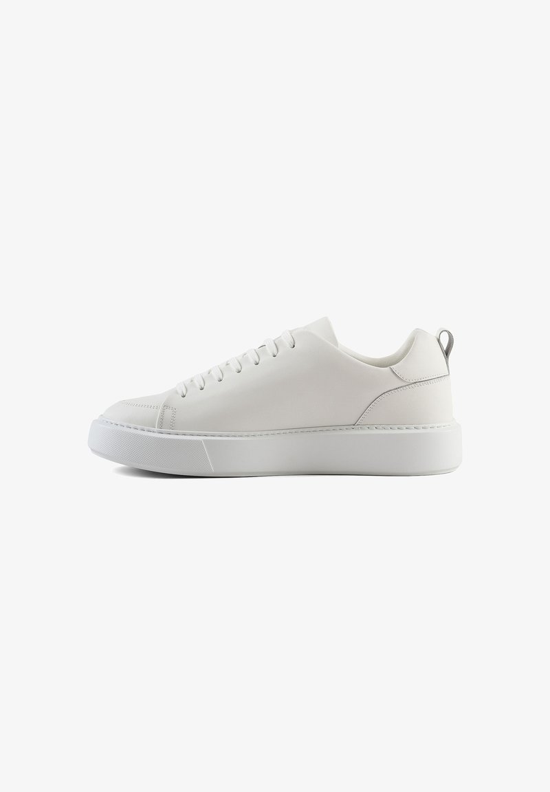 Sneaker bianca in pelle con punta arrotondata, suola in gomma bianca piatta e design minimalista; presenta un piccolo supporto sul tallone grigio e sei passanti.