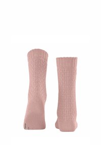 Chaussettes tricotées roses avec un motif texturé et une finition côtelée. Le corps présente de petits points en relief, offrant une apparence douce et un ajustement confortable.