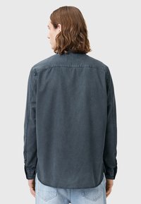 Maglietta a maniche lunghe grigio scuro con colletto button-down, cuciture a contrasto e orlo curvo. Tessuto liscio con una vestibilità comoda.
