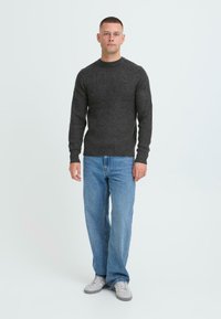 Mørkegrå tekstureret sweater med rund hals, kombineret med lys blå løstsiddende jeans og lys grå sneakers.
