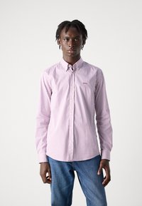 Camisa de manga larga de botones en rosa claro con rayas blancas, con cuello y corte regular. Logo distintivo en el pecho.