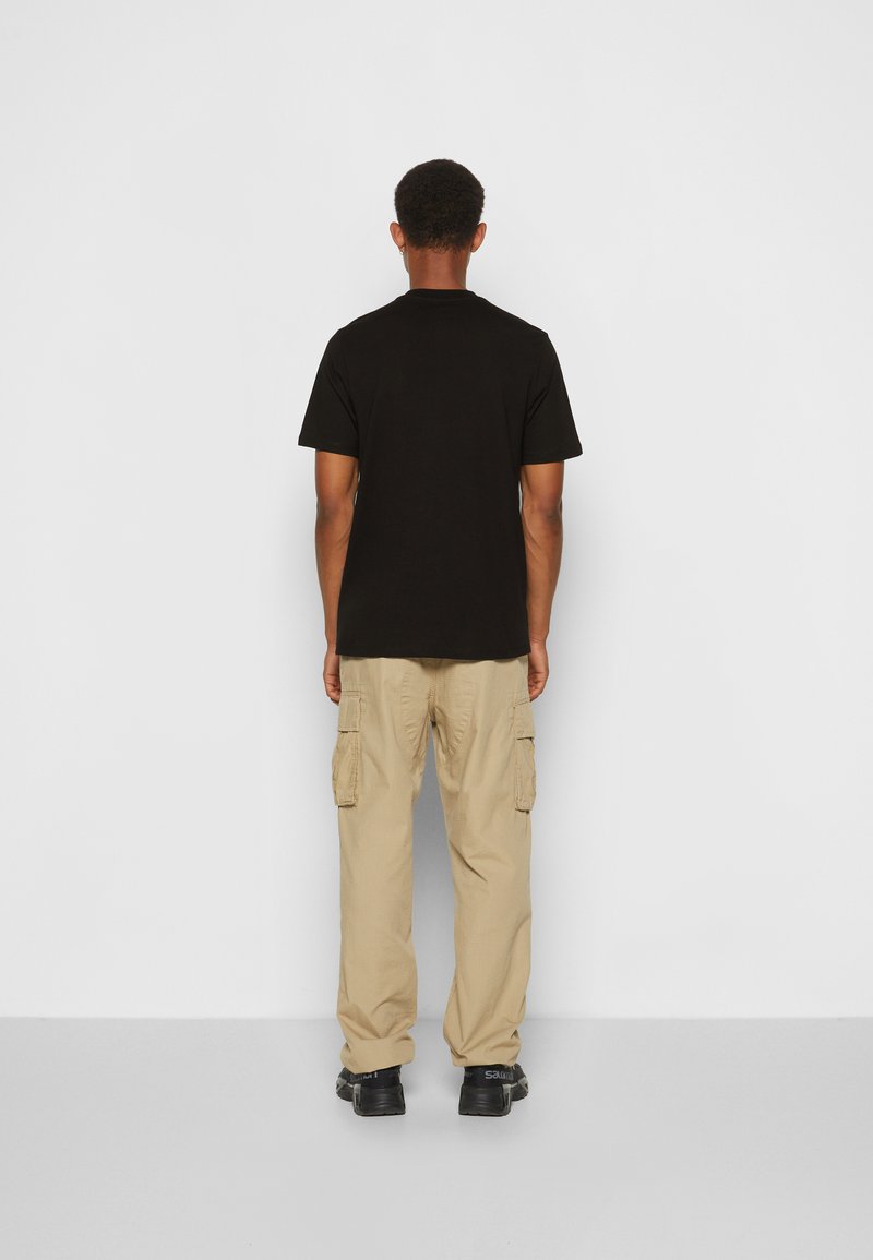 Schwarzes Baumwoll-T-Shirt mit klassischem Rundhalsausschnitt, kombiniert mit beigen Cargo-Hosen, die seitliche Taschen und eine lockere Passform aufweisen.