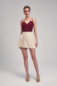 Burgundin ribbad linne med tunna axelband, i kombination med en krämfärgad kjol i kort modell med skräddarsydd design och sidofickor. Bärs med nude-höga klackar.