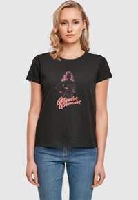 Sort kortærmet T-shirt med et pink grafik af Wonder Woman og fed skrift nedenunder; lavet af blødt bomuldsstof.