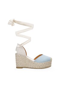 Sandalia cuña de lona azul con suela de yute trenzado, envoltura de tobillo blanca con estampado y diseño de punta abierta. Presenta un upper texturizado y acolchado.