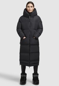 Garšs melns pufis ar augstu kapuci, rāvējslēdzēja aizdare, sānu kabatām un izšuvumu dizainu. Kombinēts ar melniem zābakiem. Gluda tekstūra.