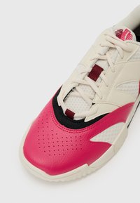 Sneaker featuring a white mesh upper, pink leather toe cap, black accents, textured detailing, and beige sole with circular patterns.
