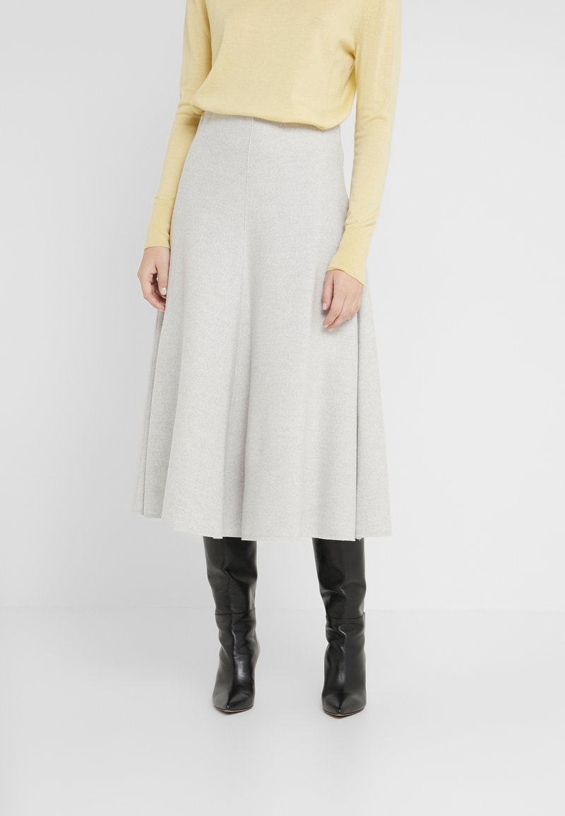 Jasnoszara, do kolan, rozkloszowana spódnica z miękkiego materiału, o gładkiej strukturze i wysokim stanie, zestawiona z żółtą bluzką z długim rękawem i czarnymi botkami.