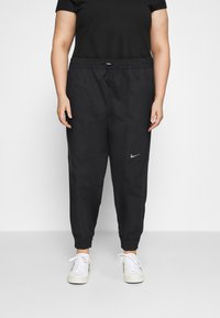 Svarta Nike-joggingbyxor med elastisk midja, smalnande ben och sidofickor. Har en liten silverfärgad logotyp på vänstra låret.