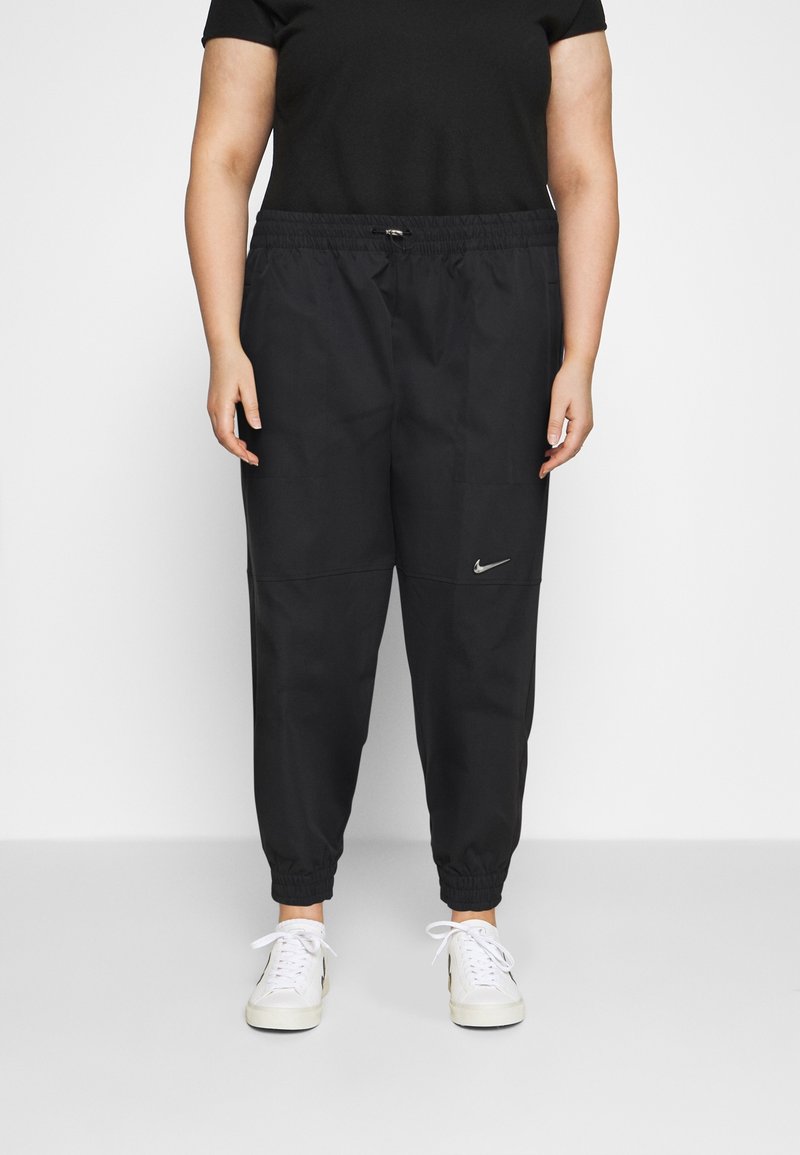 Svarta Nike-joggingbyxor med elastisk midja, smalnande ben och sidofickor. Har en liten silverfärgad logotyp på vänstra låret.