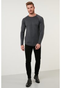 Top gri cu mânecă lungă din tricot ribat, cu decolteu rotund, asociat cu pantaloni negri ajustați și cizme negre până la gleznă. Design simplu și elegant.