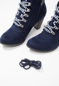 Donkerblauwe suède enkellaarsjes met een gestructureerde afwerking, voorzien van zilverkleurige hardware en geruite veters; inclusief een extra donkerblauwe veter.