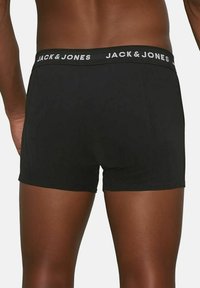Schwarze Boxershorts mit enganliegendem Schnitt, aus weichem Stoff gefertigt. Der Bund zeigt weißen Text "JACK & JONES" in einem sich wiederholenden Muster.