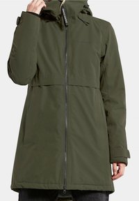 Abrigo impermeable verde oliva con cremallera en la parte delantera, capucha ajustable y puños doblados. Presenta una textura suave y un diseño minimalista.