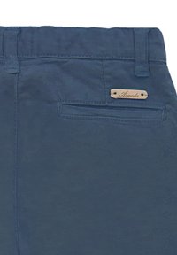 Pantalones de algodón azul marino con un bolsillo trasero y una etiqueta de cuero marrón claro con la inscripción "Aranda" grabada. Textura suave y diseño de cinturilla estándar.