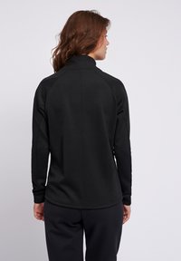 Maglietta nera a maniche lunghe con colletto alto, maniche raglan e texture liscia. Presenta un design aderente e dettagli di cucitura delicati.