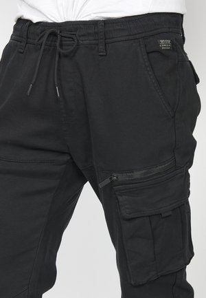 Fekete cargo nadrág rugalmas derékpánttal, zsinórzárással, elülső zsebekkel és oldalsó cipzáras zsebbel; puha, tartós anyagból készült.