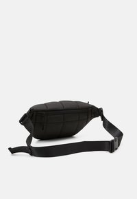 Czarna torba na ramię z pikowanym wzorem, kieszenią na zamek i regulowanym paskiem. Wykonana z trwałego materiału o smukłym, zaokrąglonym kształcie.